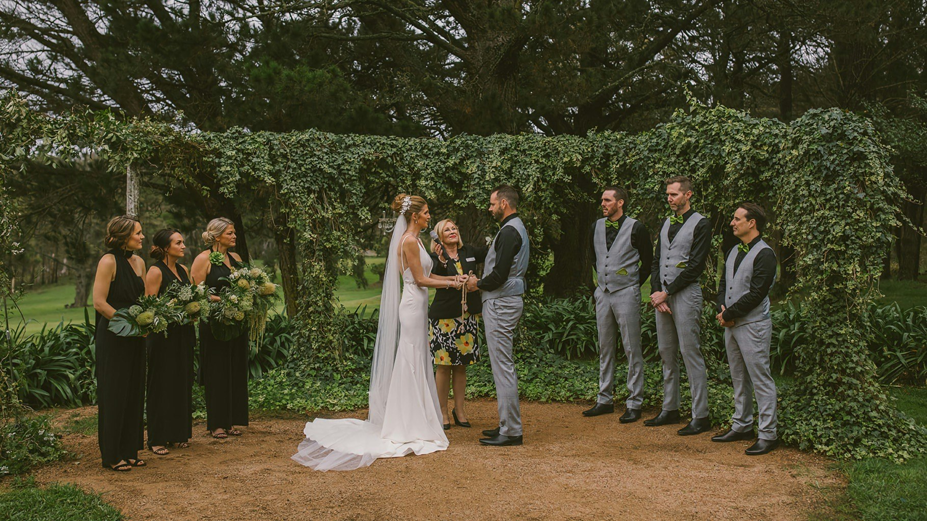 Outdoor wedding ceremony with couple holding hands.